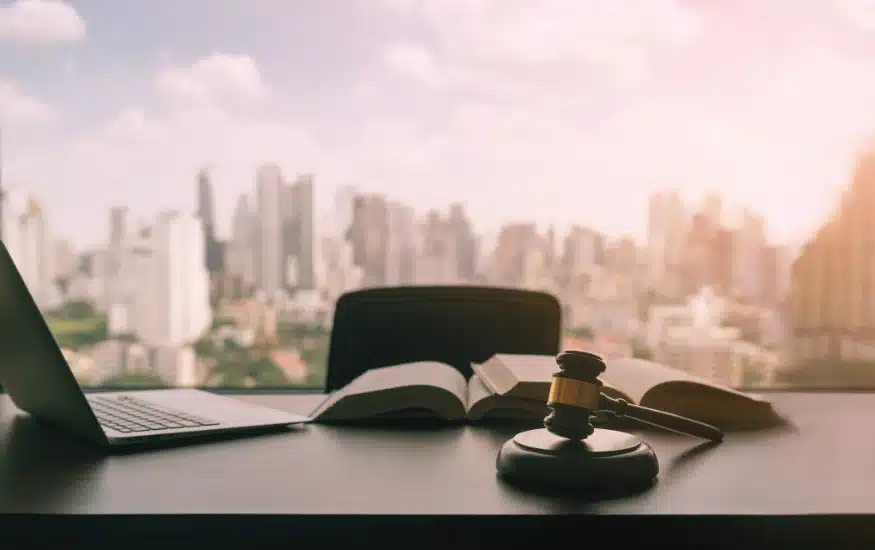 Books and a gavel atop a desk before a backdrop of a city skyline - felony lawyer in Carrollton, Georgia.